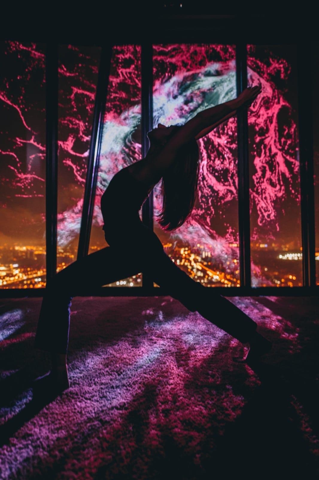 A resident stretches in front of pink and blue imagery on the panoramic windows of Cyber Zen.