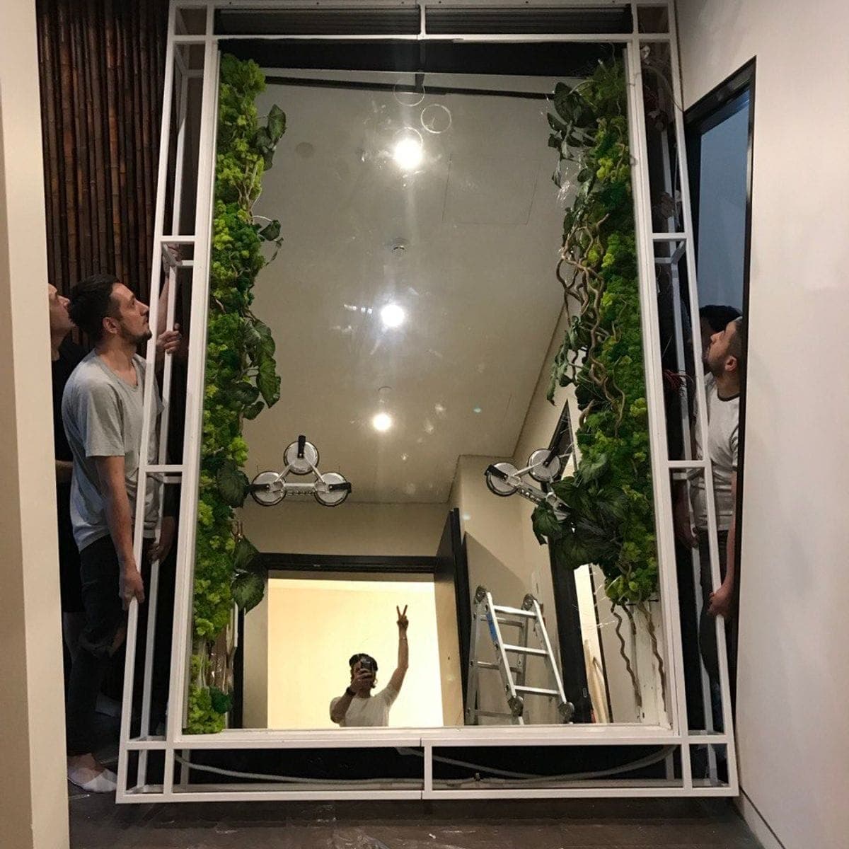 Mounting the infinity-mirror frame — the studio team setting the steel cage in the apartment hallway.