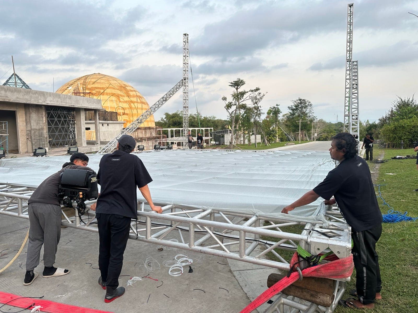 On site — three crew members tensioning the fabric across the horizontal beam, dome of Nuanu in the background.