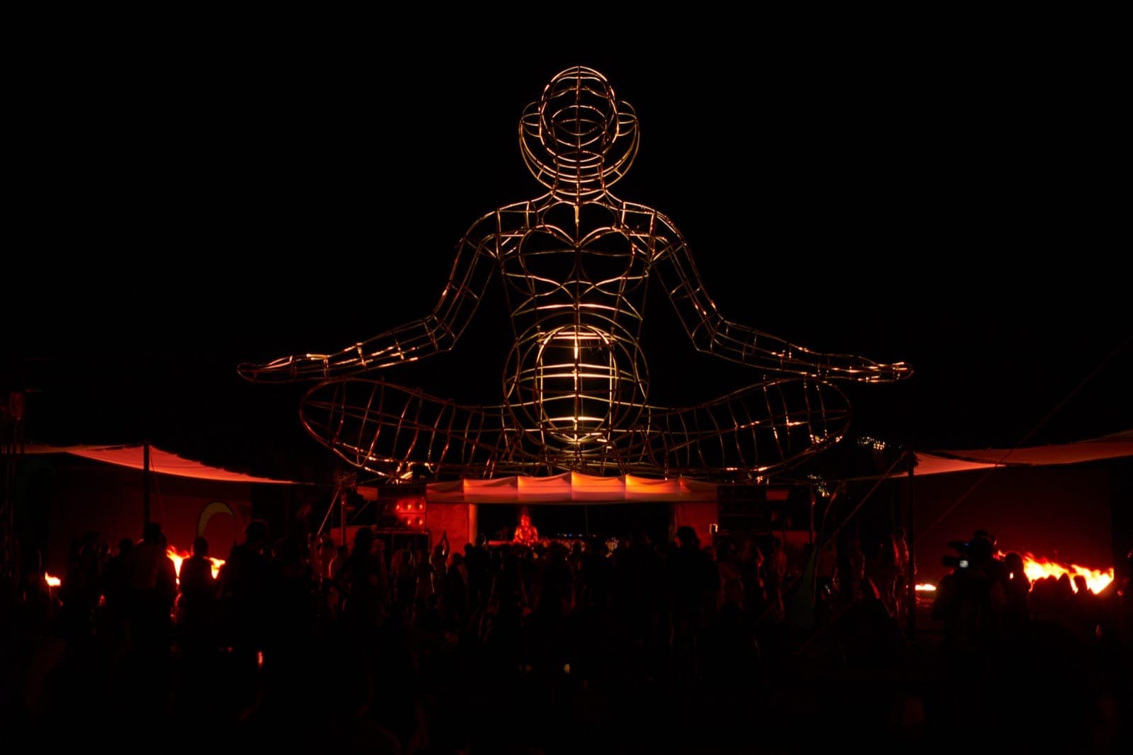 LUNA in amber light, fire effects flanking, dancers below.