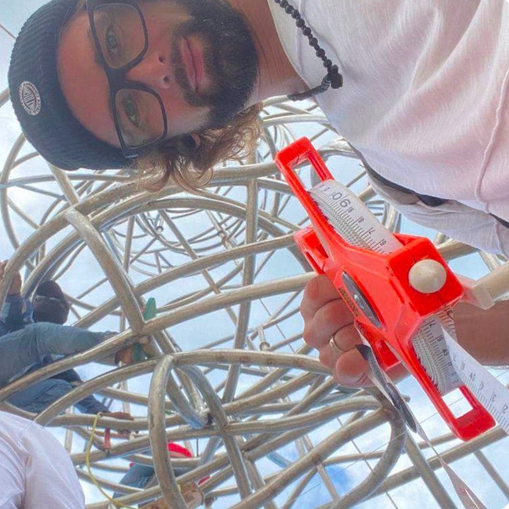 Inside LUNA — a crew member grinning up at the camera from within the wireframe sphere, calibration tool in hand.